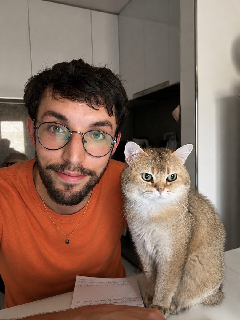 A real photo of a young man with glasses holding his golden cat