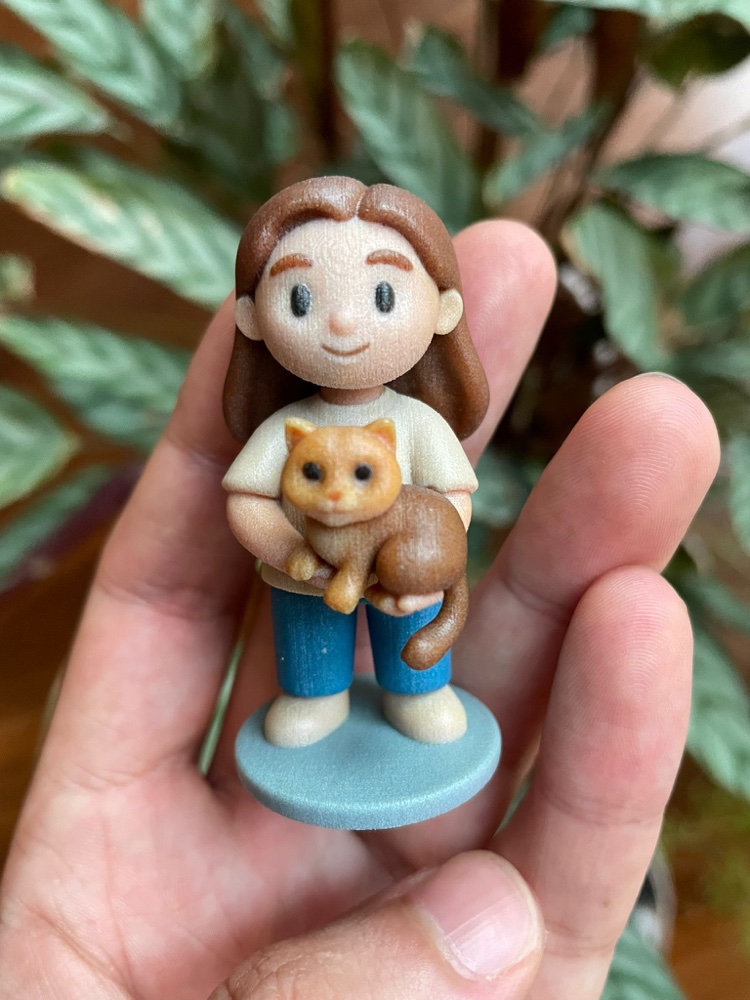Close-up of a hand holding a girl-and-cat figurine